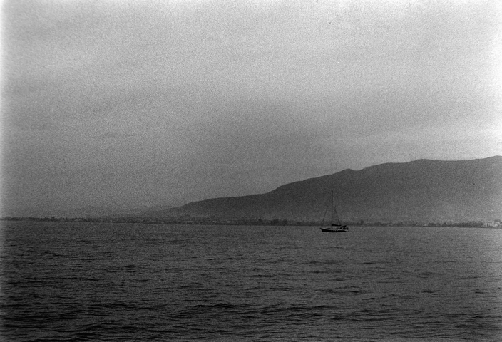 A lone sailboat in the haze of the Messinian Bay