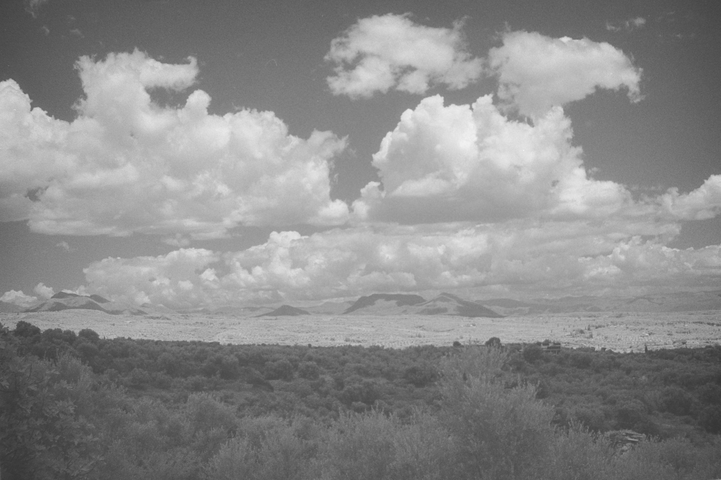 A view down from the mountains above Petalidi with the foreground in shadow and the far field in full sunlight with the upper part of the photo dominated by fluffy white clouds
