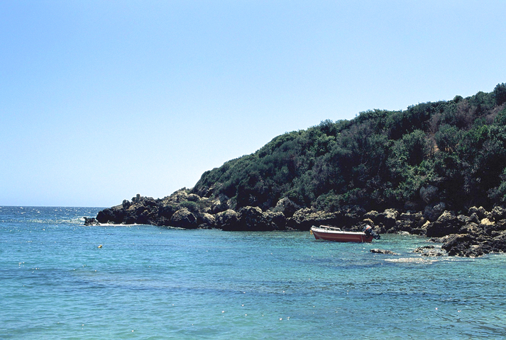 A red and yellow boat in the bay of Vromoneri