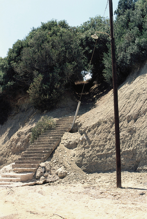 A stone and dirt staircase leading up from the beach of Vromoneri