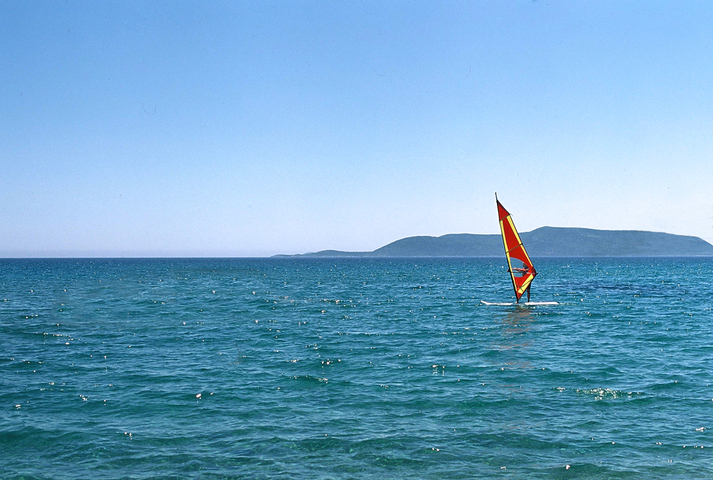 Windsurfer with a red and yellow sail in the sea